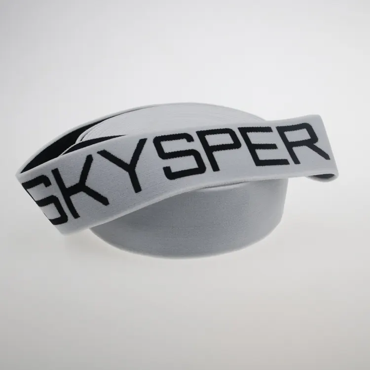 Folded white jacquard elastic webbing showing woven lettering on the face