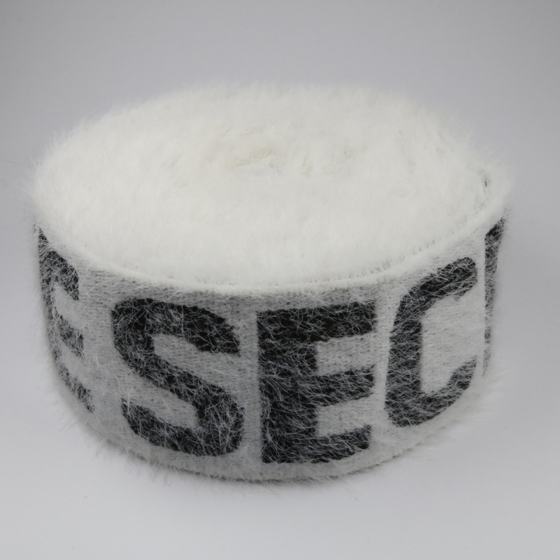 Roll of white jacquard elastic band with imitation mink velvet surface and dark woven lettering