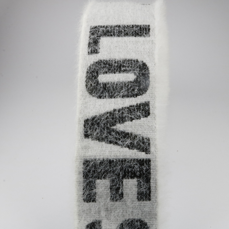 Macro view of white velvet-effect jacquard elastic band with dark woven letters