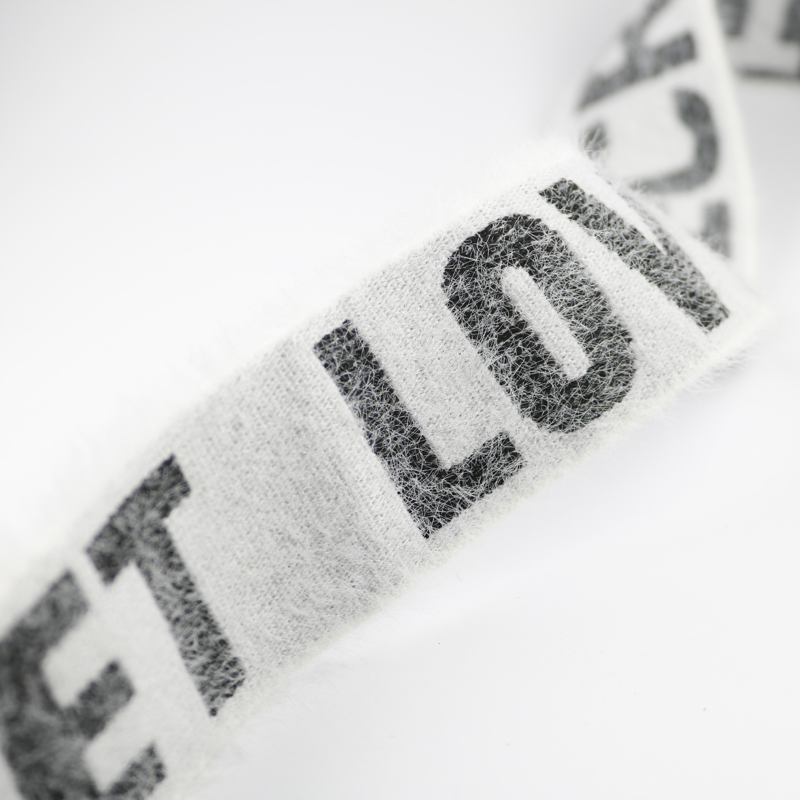 Detailed view of elastic band with imitation mink velvet effect and woven letters