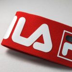 Close-up of red knitted webbing with white printed logo graphics on a white background
