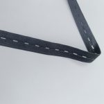 Black buttonhole elastic tape with evenly spaced buttonhole openings, folded on a white background