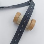 Buttonhole elastic tape with a wooden spool of cotton thread, used for adjustable waistbands
