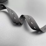 Dark grey buttonhole elastic tape draped in soft folds to show its stretch
