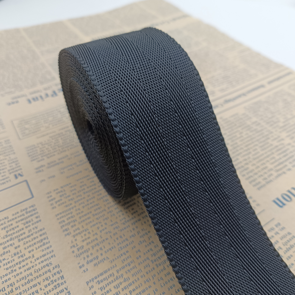 Dark navy blue high-strength polyester webbing with a herringbone twill texture, rolled and resting on printed newspaper