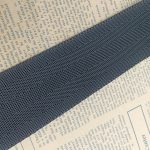 Diagonal close-up of navy blue herringbone twill webbing, highlighting the tight ribbed weave texture