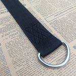 Black herringbone twill webbing with a metal D-ring sewn at the end, laid on newspaper