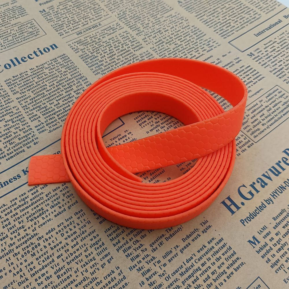 Roll of bright orange PVC-coated webbing strap with honeycomb texture, loose end folded outward on newspaper
