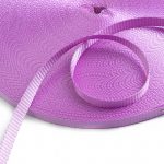 Purple woven webbing strap coiled into a roll with a loose end curving across the textured surface
