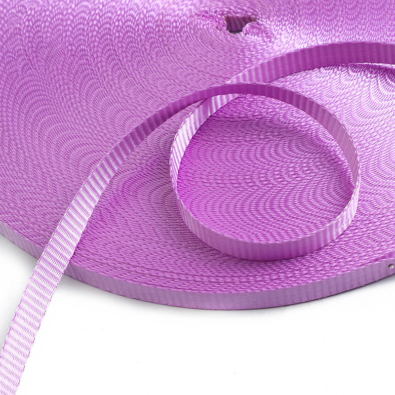 Purple woven webbing strap coiled into a roll with a loose end curving across the textured surface