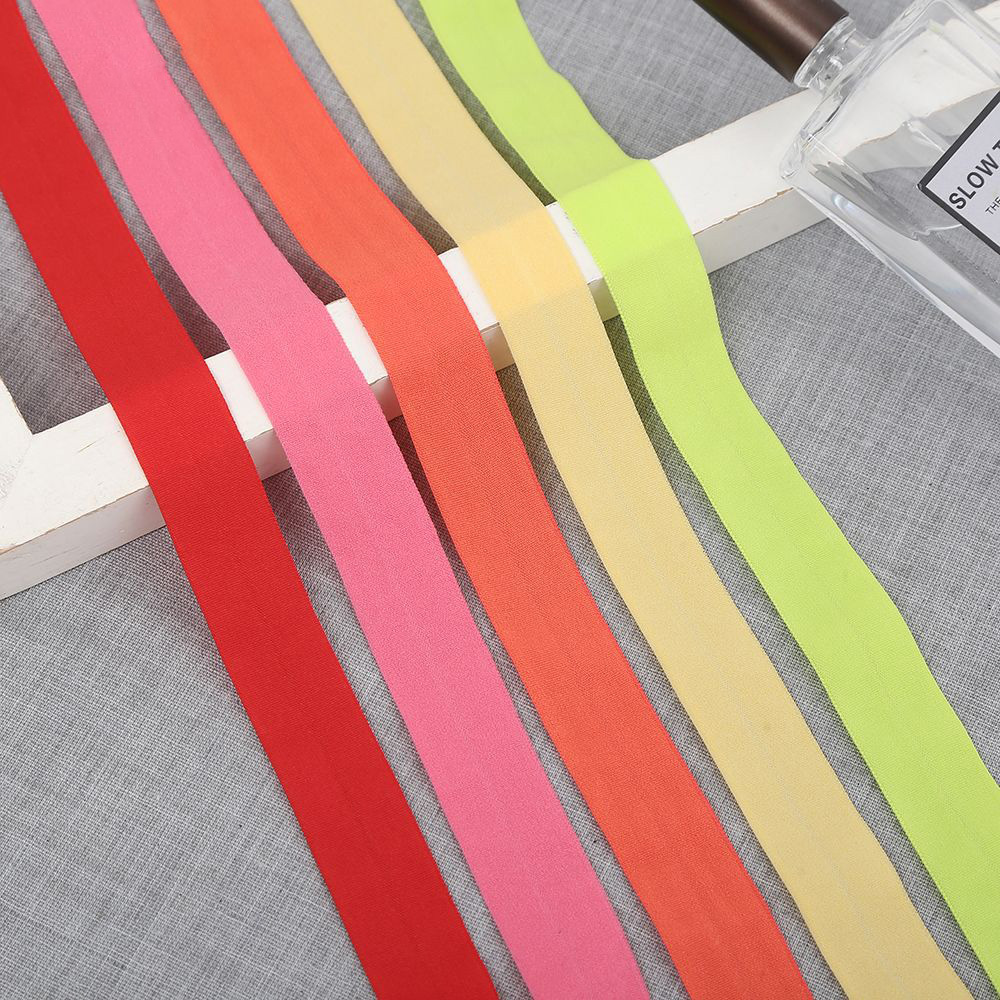 Elastic binding tape in coral red, orange, pink and lime green arranged in a fan