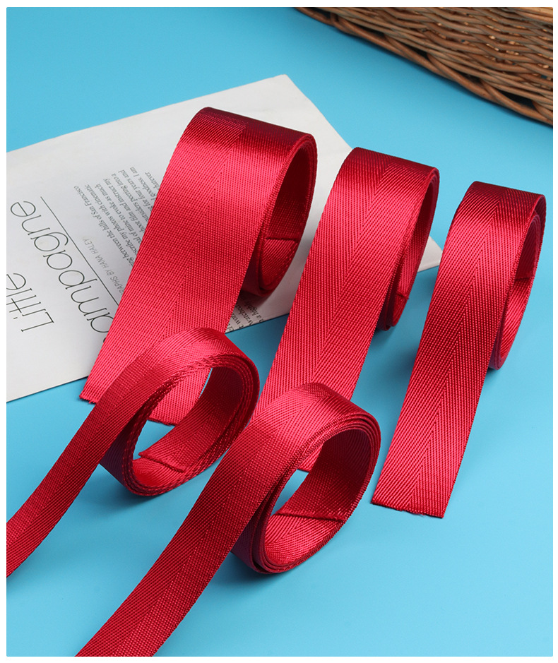Red herringbone webbing rolls in different widths with a visible twill texture