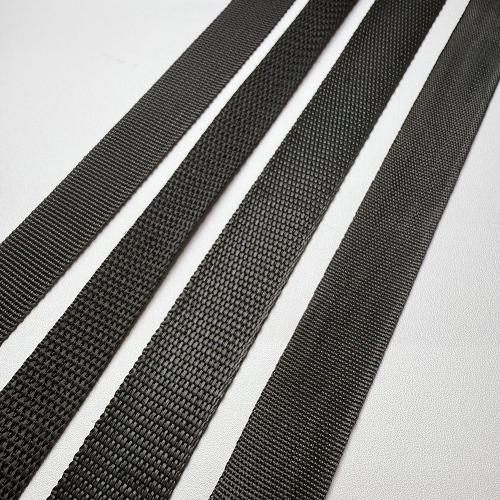 Multiple black polypropylene webbing rolls laid flat showing different widths