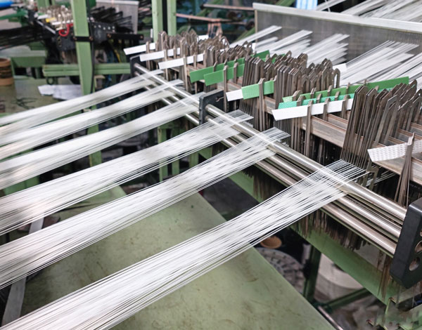 Reels of woven webbing beside an in-house tensile testing machine